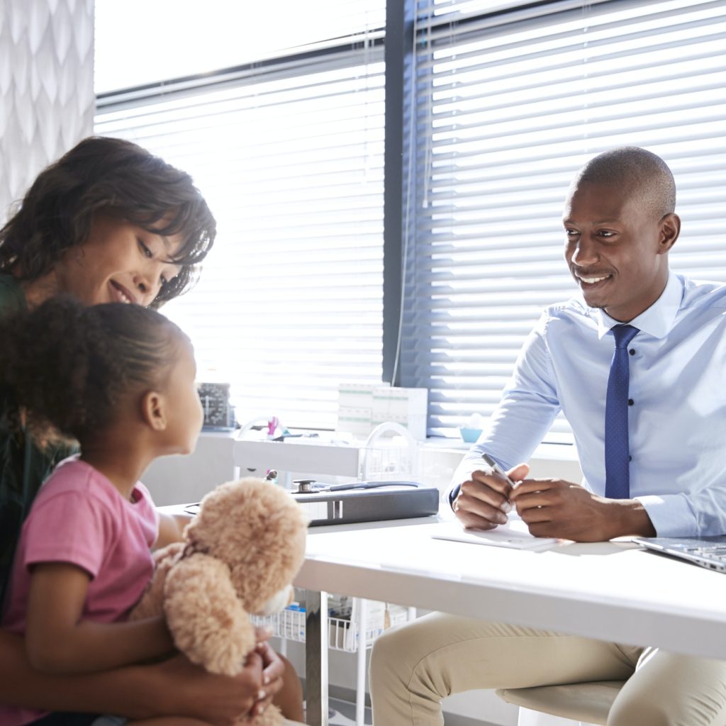 Mother And Daughter In Consultation With Doctor In Office