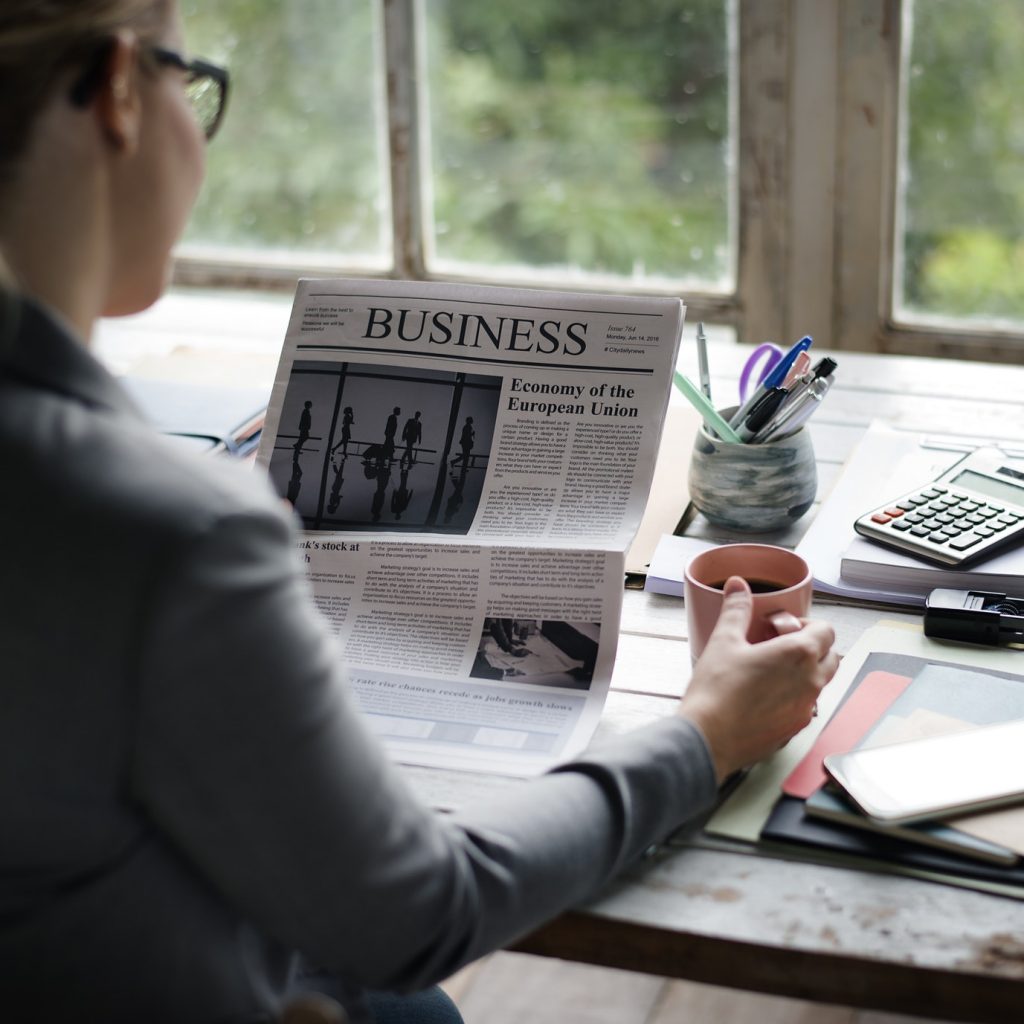 Businesspeople Reading Newspaper at Office Updating News